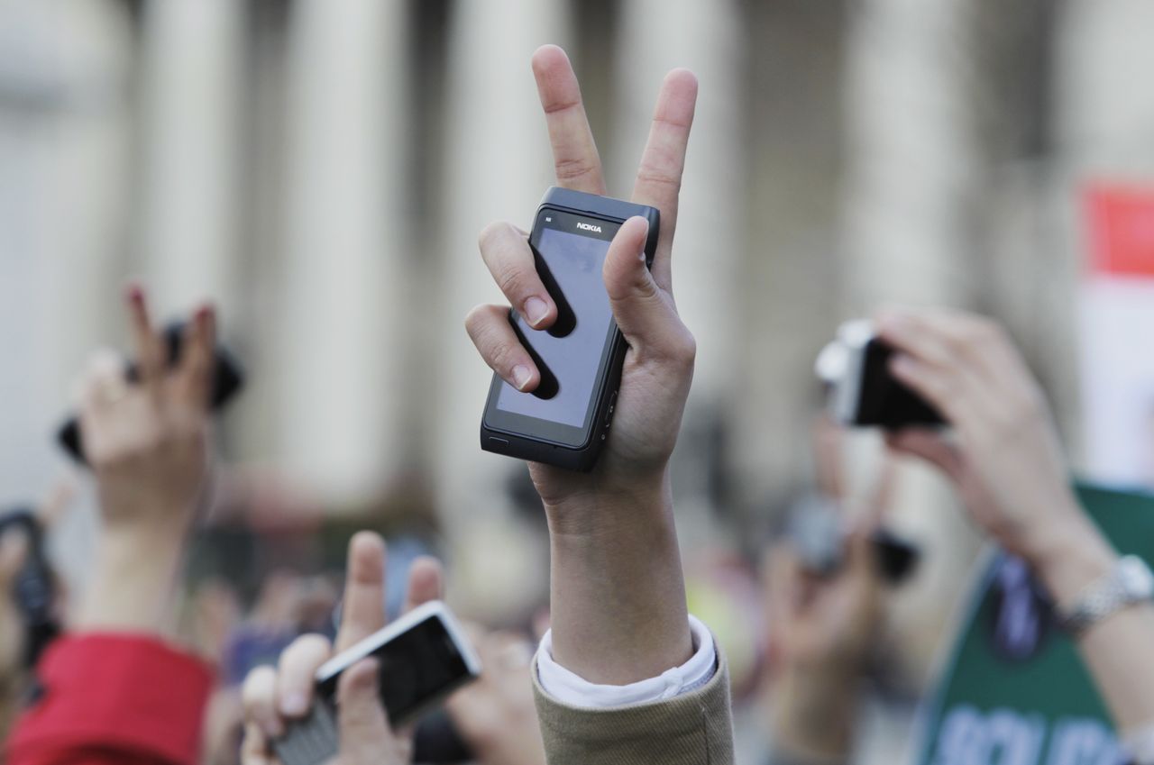A raised hand in Tahrir square with a smartphone